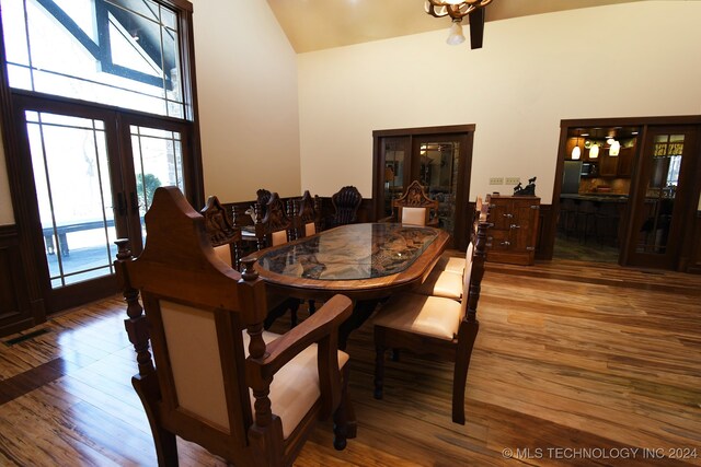 dining space with high vaulted ceiling and hardwood / wood-style flooring