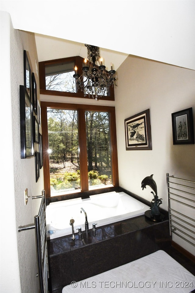 bathroom with lofted ceiling, a chandelier, plenty of natural light, and tiled bath