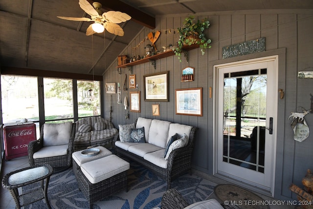 living room featuring lofted ceiling with beams, wood walls, and a healthy amount of sunlight