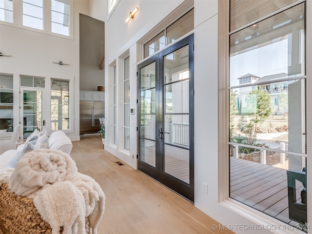 entryway featuring french doors, light hardwood / wood-style floors, and a high ceiling