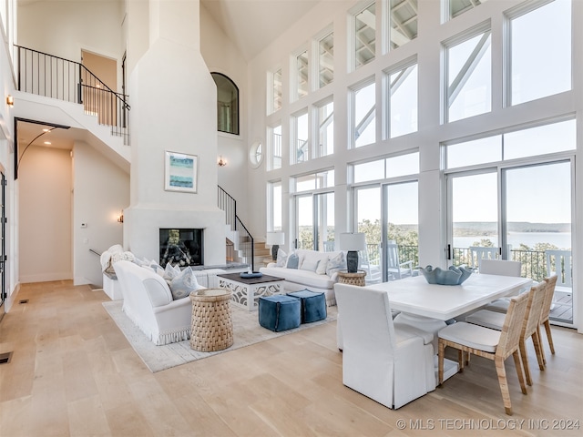 living room with a towering ceiling, a water view, and light wood-type flooring