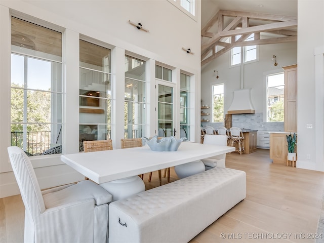 dining space with beam ceiling, high vaulted ceiling, and light wood-type flooring