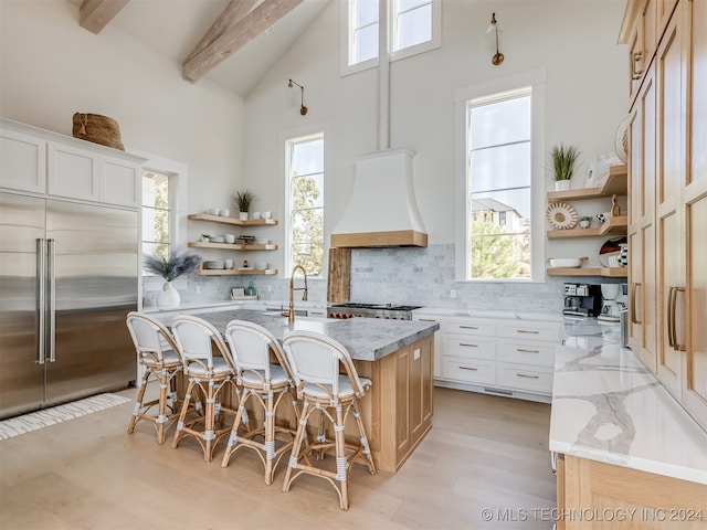 kitchen featuring white cabinetry, stainless steel appliances, plenty of natural light, and a center island with sink