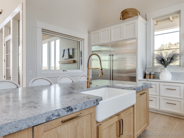 kitchen featuring light brown cabinets, stainless steel built in refrigerator, and plenty of natural light