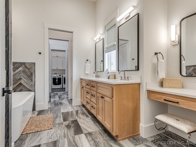 bathroom with vanity, a tub, and separate washer and dryer