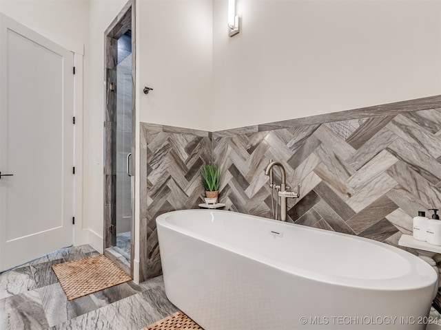 bathroom featuring shower with separate bathtub and tile walls