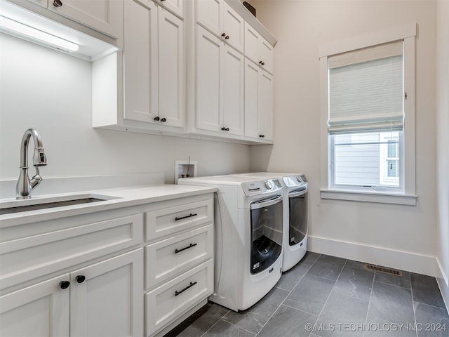 laundry area featuring dark tile patterned floors, sink, washer and dryer, and cabinets