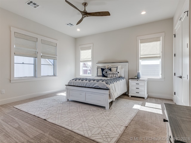 bedroom featuring ceiling fan, multiple windows, and light colored carpet