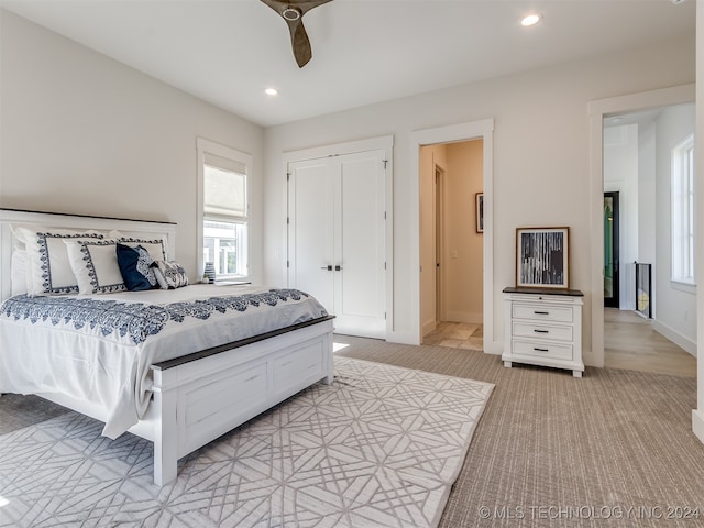 bedroom featuring a closet, ceiling fan, and light carpet