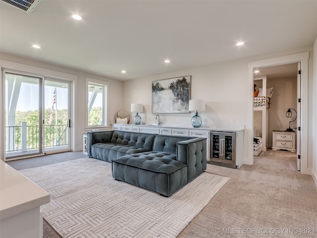 living room with light colored carpet, beverage cooler, and sink