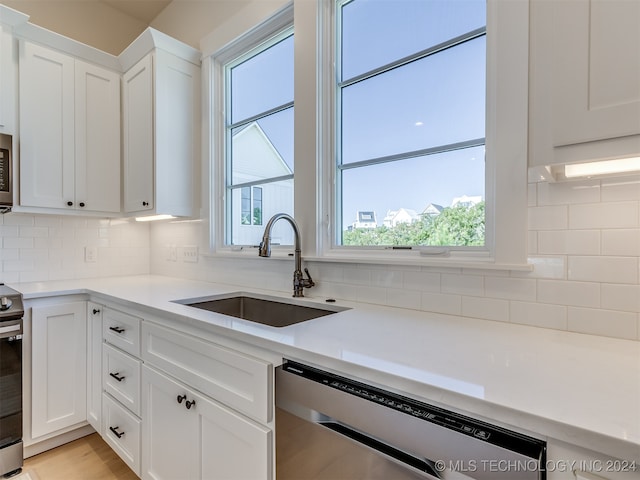 kitchen featuring stainless steel appliances, decorative backsplash, sink, and white cabinets