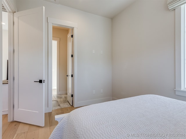 bedroom with ensuite bathroom and light wood-type flooring