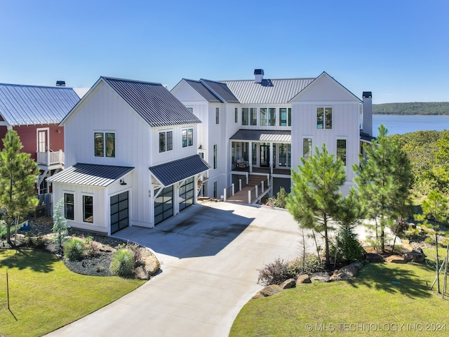 modern farmhouse featuring a front yard, a garage, and a water view