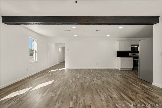 unfurnished living room with beam ceiling and hardwood / wood-style flooring