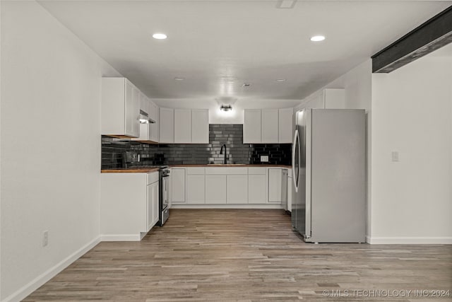 kitchen with decorative backsplash, light wood-type flooring, stainless steel appliances, sink, and white cabinetry