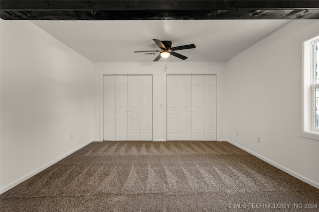 unfurnished bedroom with carpet flooring, ceiling fan, and multiple closets