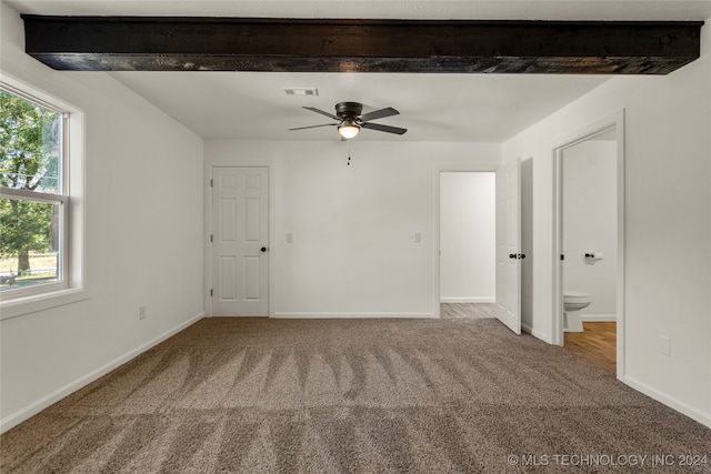 carpeted empty room with beam ceiling, a wealth of natural light, and ceiling fan