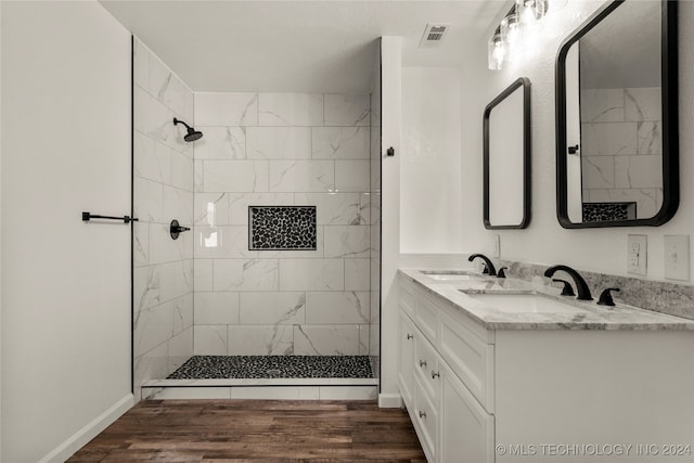 bathroom with hardwood / wood-style floors, vanity, and a tile shower