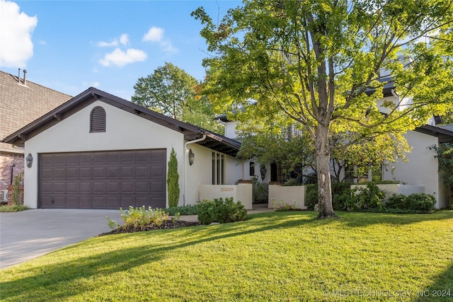 ranch-style home featuring a garage and a front lawn