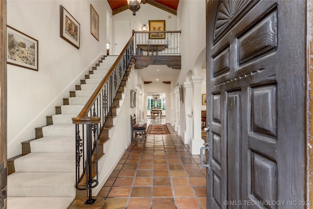 foyer entrance with beam ceiling, ornate columns, and high vaulted ceiling