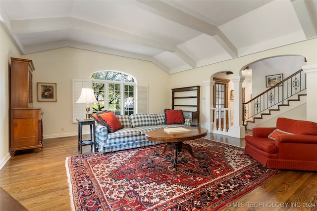 living room featuring decorative columns, lofted ceiling with beams, and hardwood / wood-style flooring