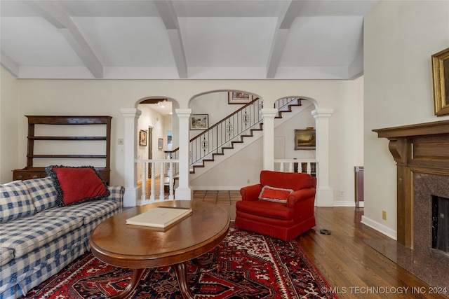 living room with a high end fireplace, beam ceiling, and dark hardwood / wood-style flooring