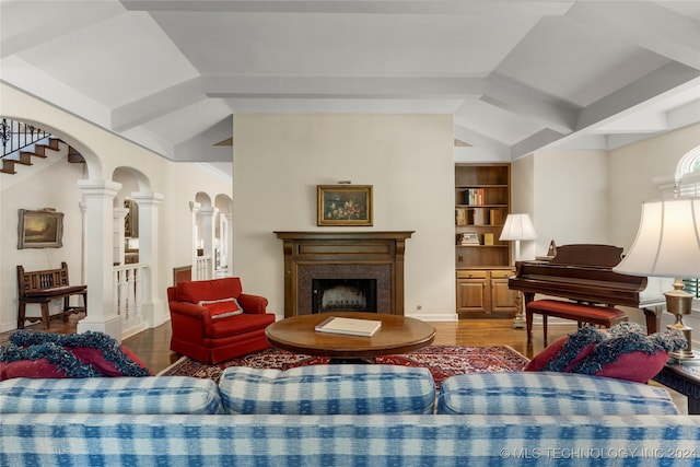 living room with wood-type flooring, vaulted ceiling, built in shelves, and ornate columns