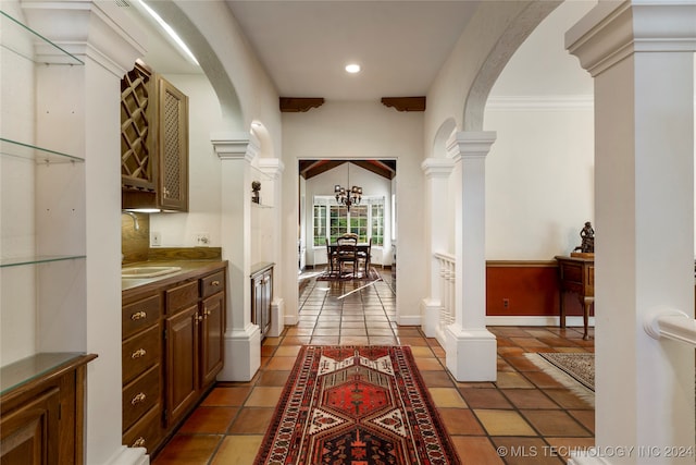 hall with crown molding, sink, tile patterned floors, and a notable chandelier