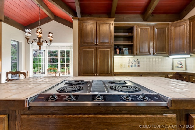 kitchen featuring decorative backsplash, vaulted ceiling with beams, tile counters, and hanging light fixtures