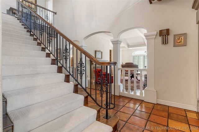 staircase with ornate columns and tile patterned floors