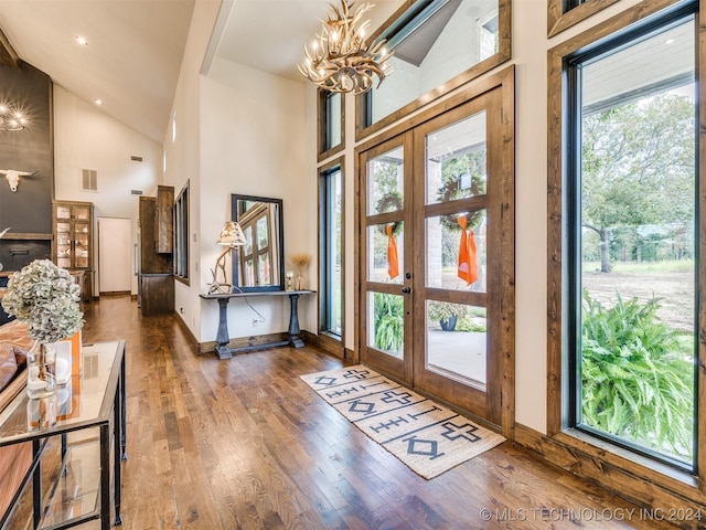 foyer featuring a notable chandelier, a towering ceiling, dark wood-type flooring, and french doors