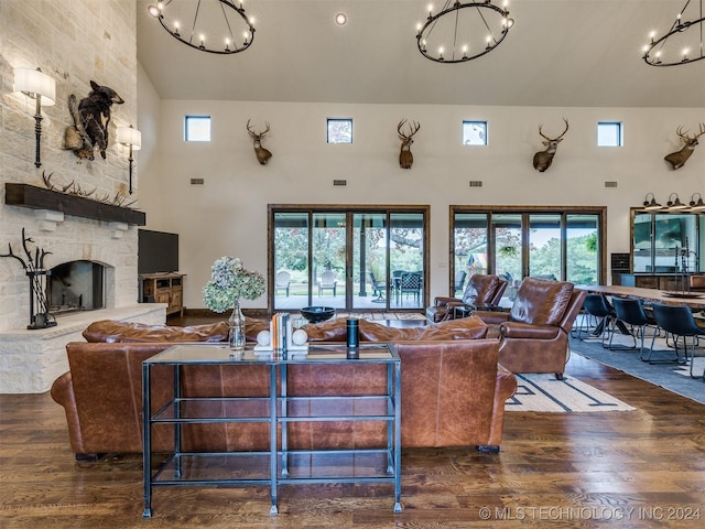 living room featuring a towering ceiling, a stone fireplace, and dark wood-type flooring