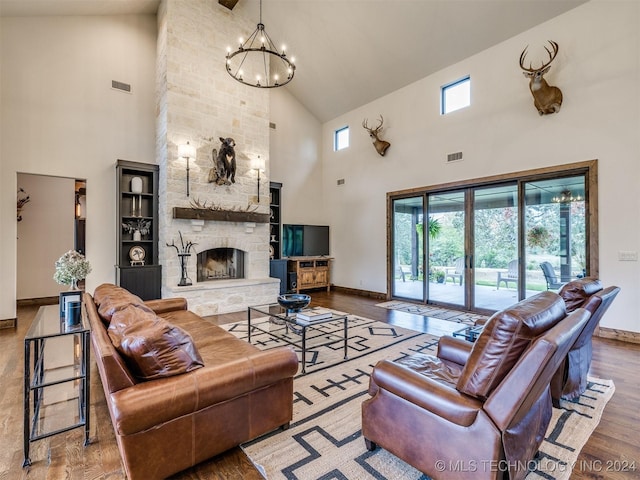 living room with hardwood / wood-style flooring, a notable chandelier, a fireplace, and high vaulted ceiling