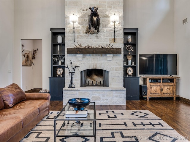 living room featuring built in shelves, a fireplace, and dark wood-type flooring