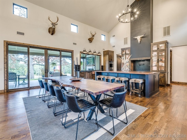 dining space featuring a high ceiling, an inviting chandelier, and dark wood-type flooring