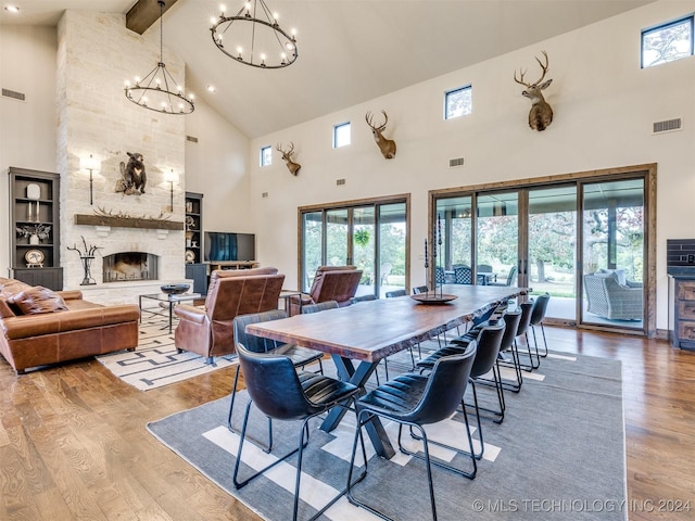 dining space featuring beam ceiling, light hardwood / wood-style floors, a fireplace, and high vaulted ceiling