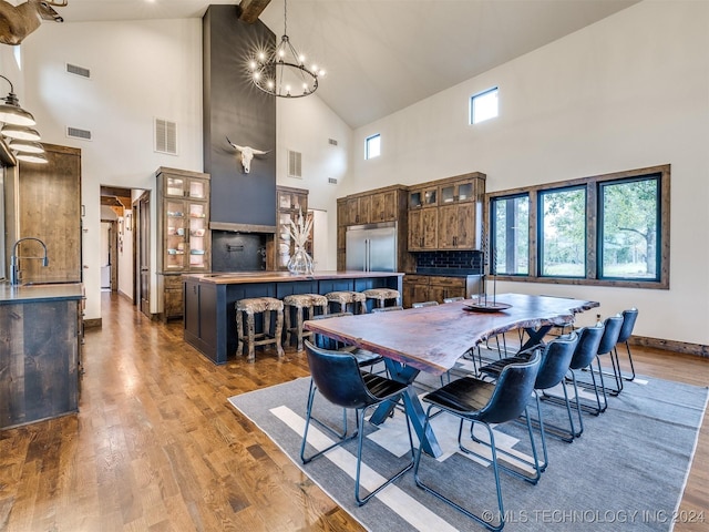 dining space with sink, beamed ceiling, high vaulted ceiling, a chandelier, and wood-type flooring