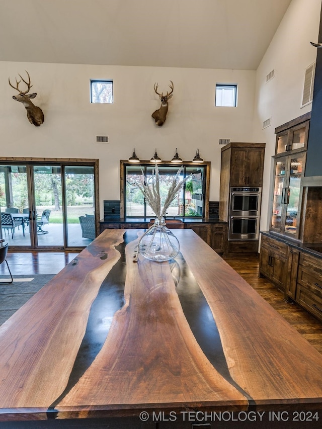 dining room featuring a towering ceiling, dark wood-type flooring, and french doors