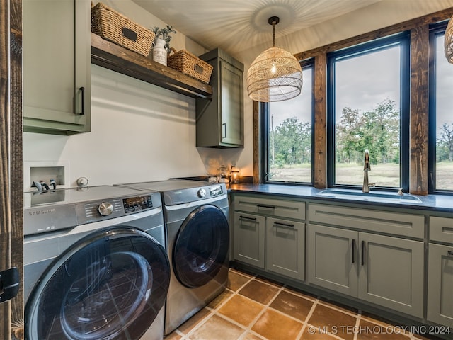 clothes washing area featuring cabinets, washer and dryer, and sink