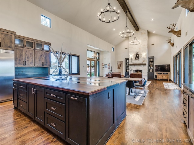 kitchen with a center island, backsplash, a stone fireplace, built in refrigerator, and butcher block countertops