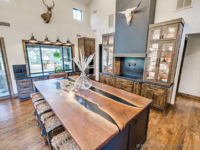 kitchen featuring sink, a center island, a high ceiling, dark hardwood / wood-style floors, and black electric cooktop