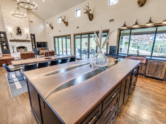 kitchen featuring high vaulted ceiling, light hardwood / wood-style flooring, a kitchen island, and a wealth of natural light