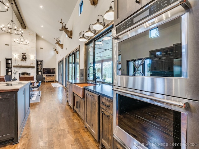 kitchen with sink, high vaulted ceiling, wooden counters, double oven, and decorative light fixtures