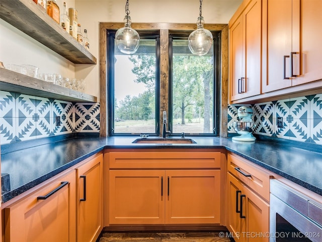 kitchen featuring wall oven, decorative backsplash, sink, and decorative light fixtures