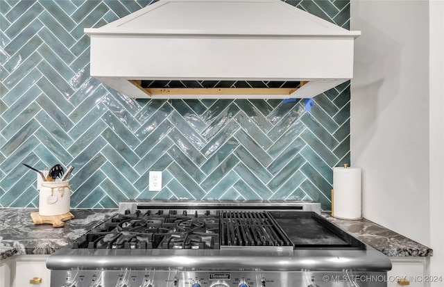 interior details featuring dark stone counters, backsplash, stove, and custom range hood