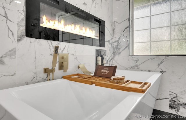 bathroom with tile walls, plenty of natural light, and a bathtub