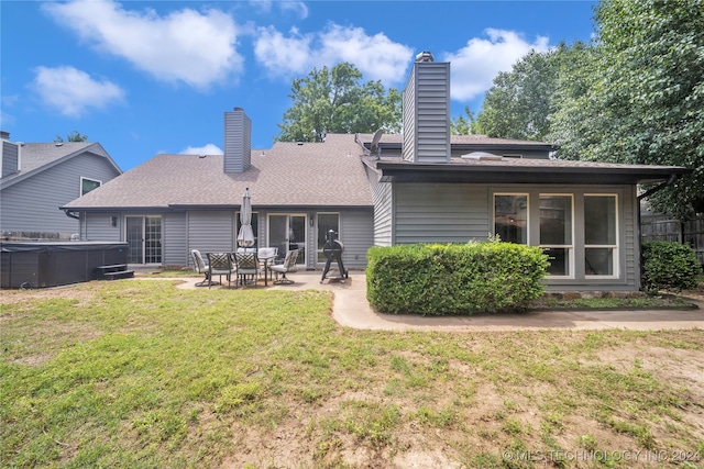 back of property featuring a hot tub, a patio area, and a yard