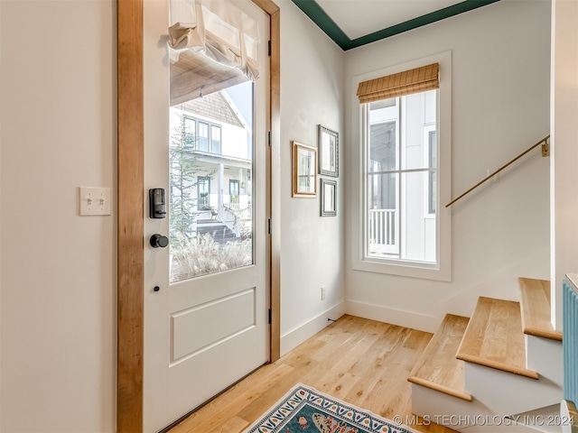 doorway to outside featuring wood-type flooring and ornamental molding