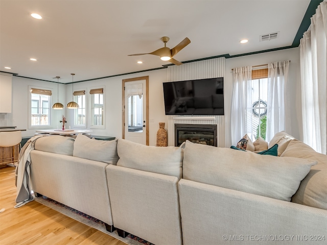 living room with light wood-type flooring, ceiling fan, and crown molding