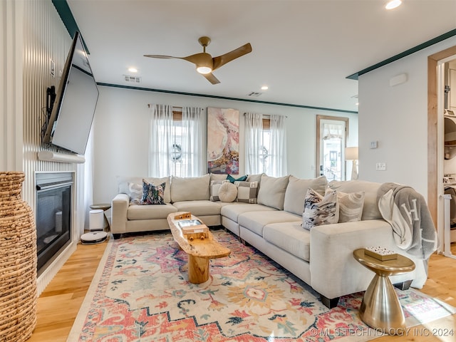 living room with light hardwood / wood-style flooring, ceiling fan, and ornamental molding